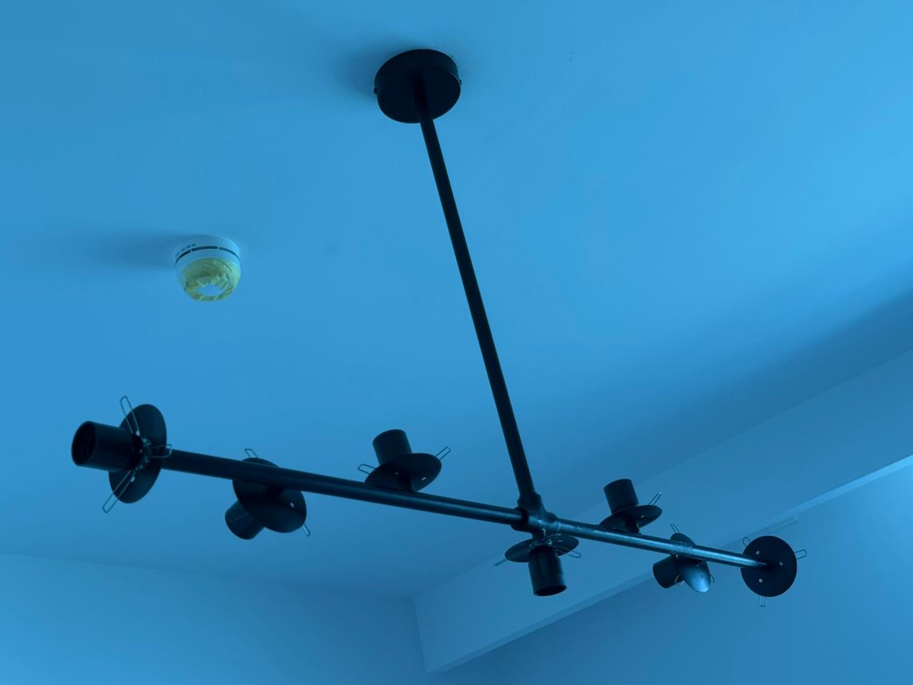 Blue and chrome artistic chandelier being mounted in UAE residential space
