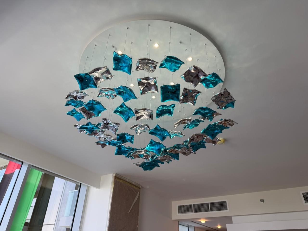 Large modern chandelier being installed with professional scaffolding in UAE hotel lobby