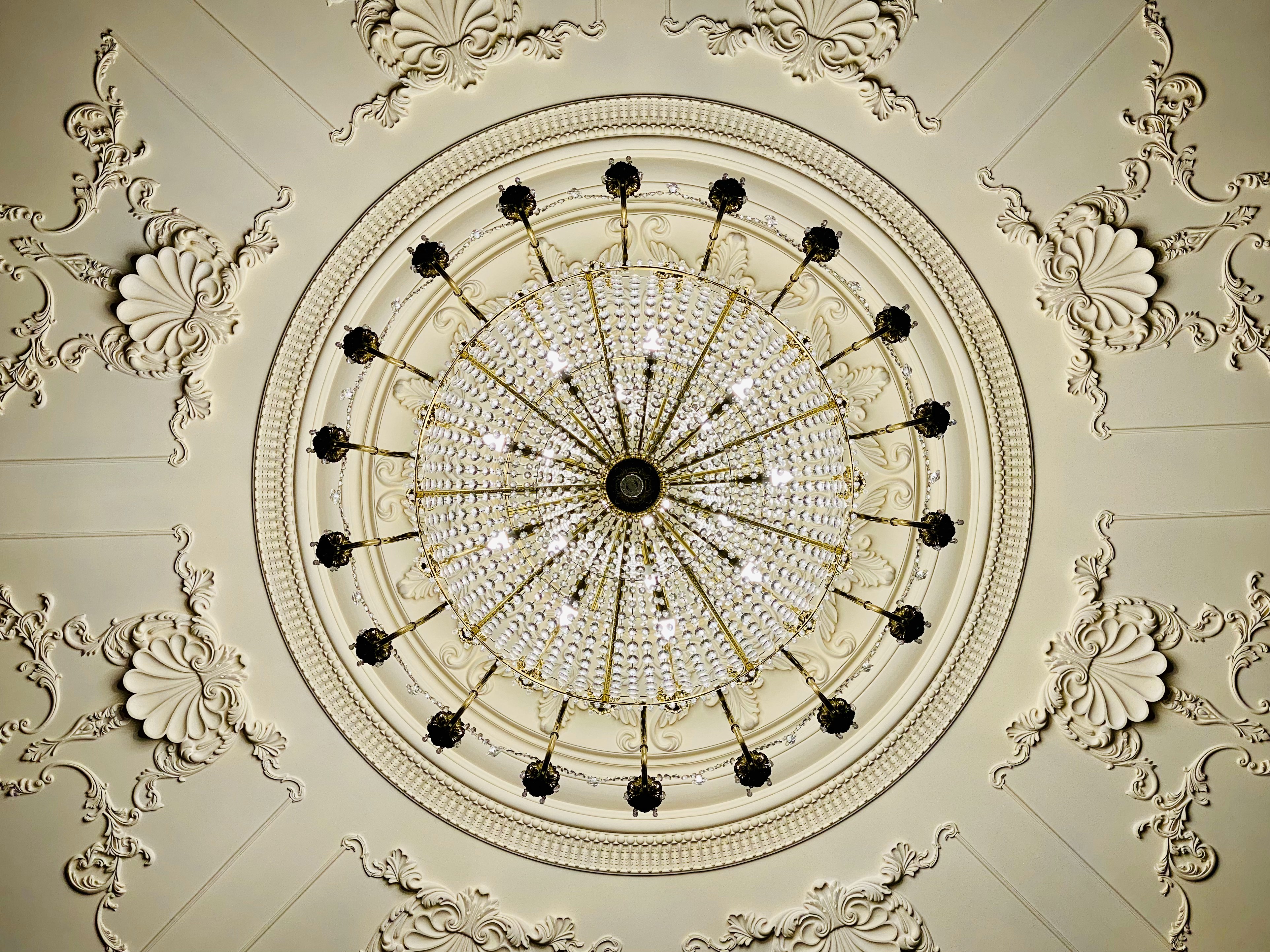 Top-down view of a circular crystal chandelier with ornate ceiling